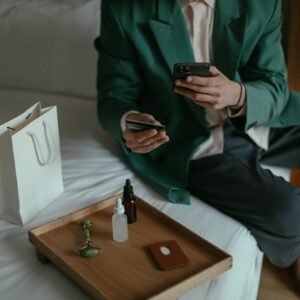 Anonymous man using smartphone while placing order with credit card sitting near cosmetic products